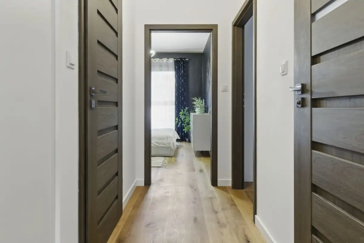 Bright hallway in Warsaw apartment with wooden doors and natural light from bedroom.