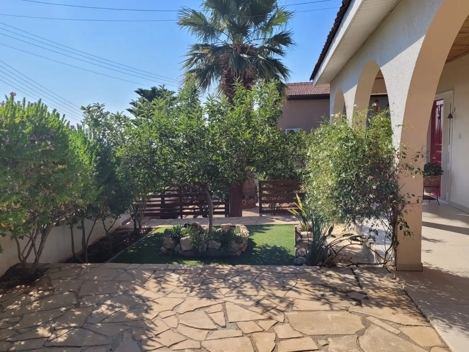 Modern Mediterranean villa garden with lush greenery and palm trees.
