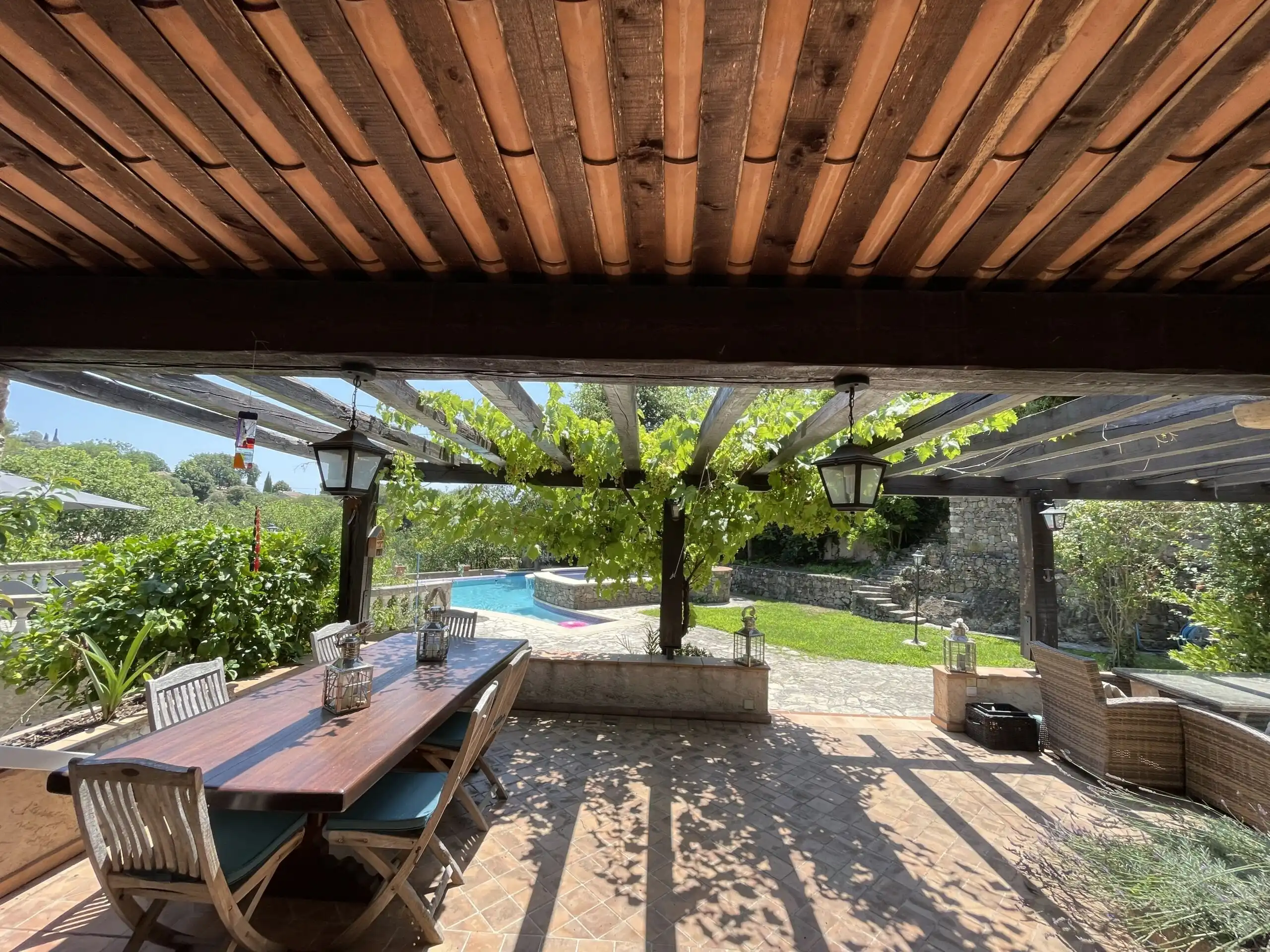 Elegant outdoor dining space with wooden furniture and lush garden views in Biot, French Riviera.