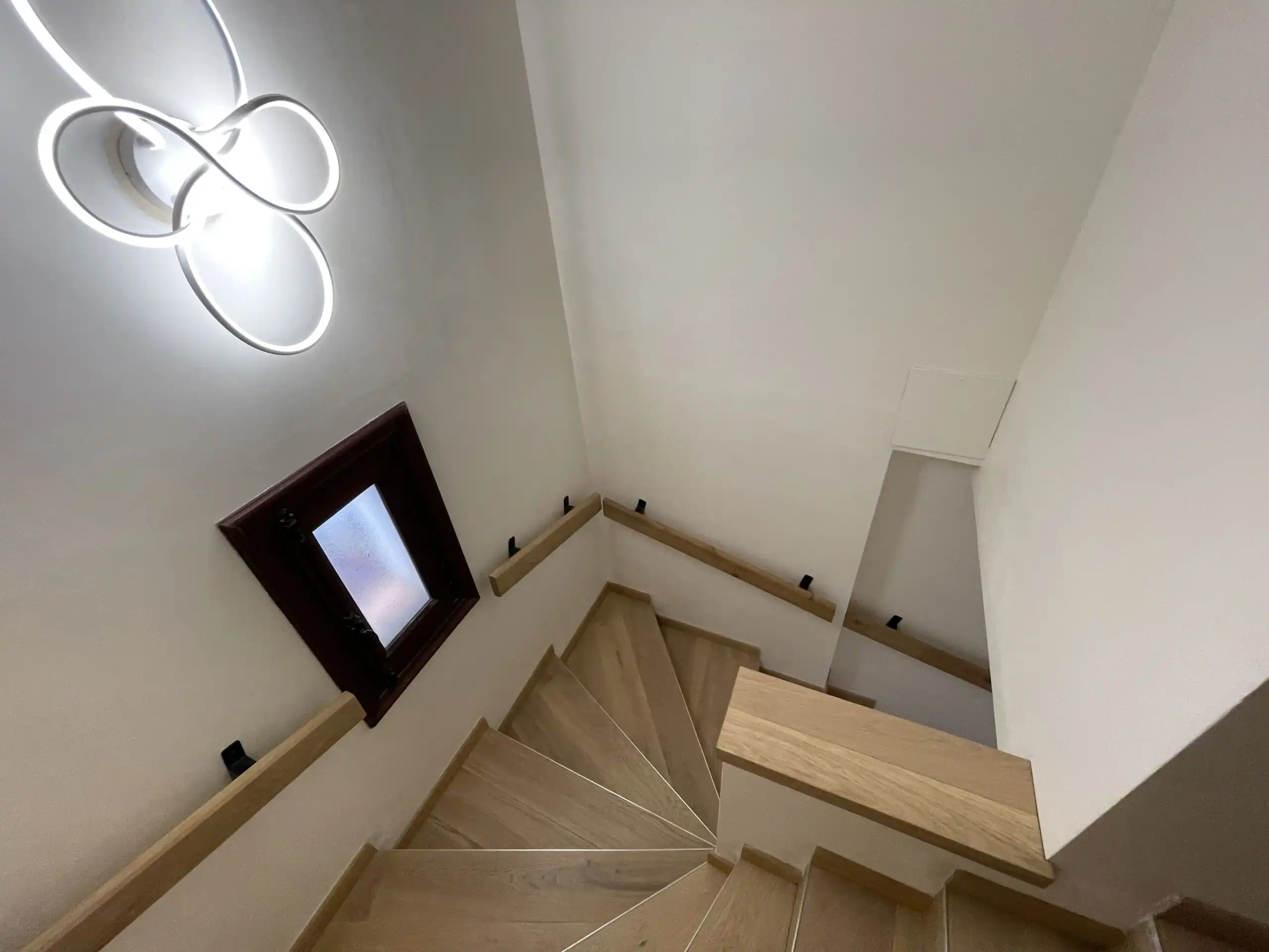 Elegant staircase in a renovated villa with modern lighting and wooden accents.