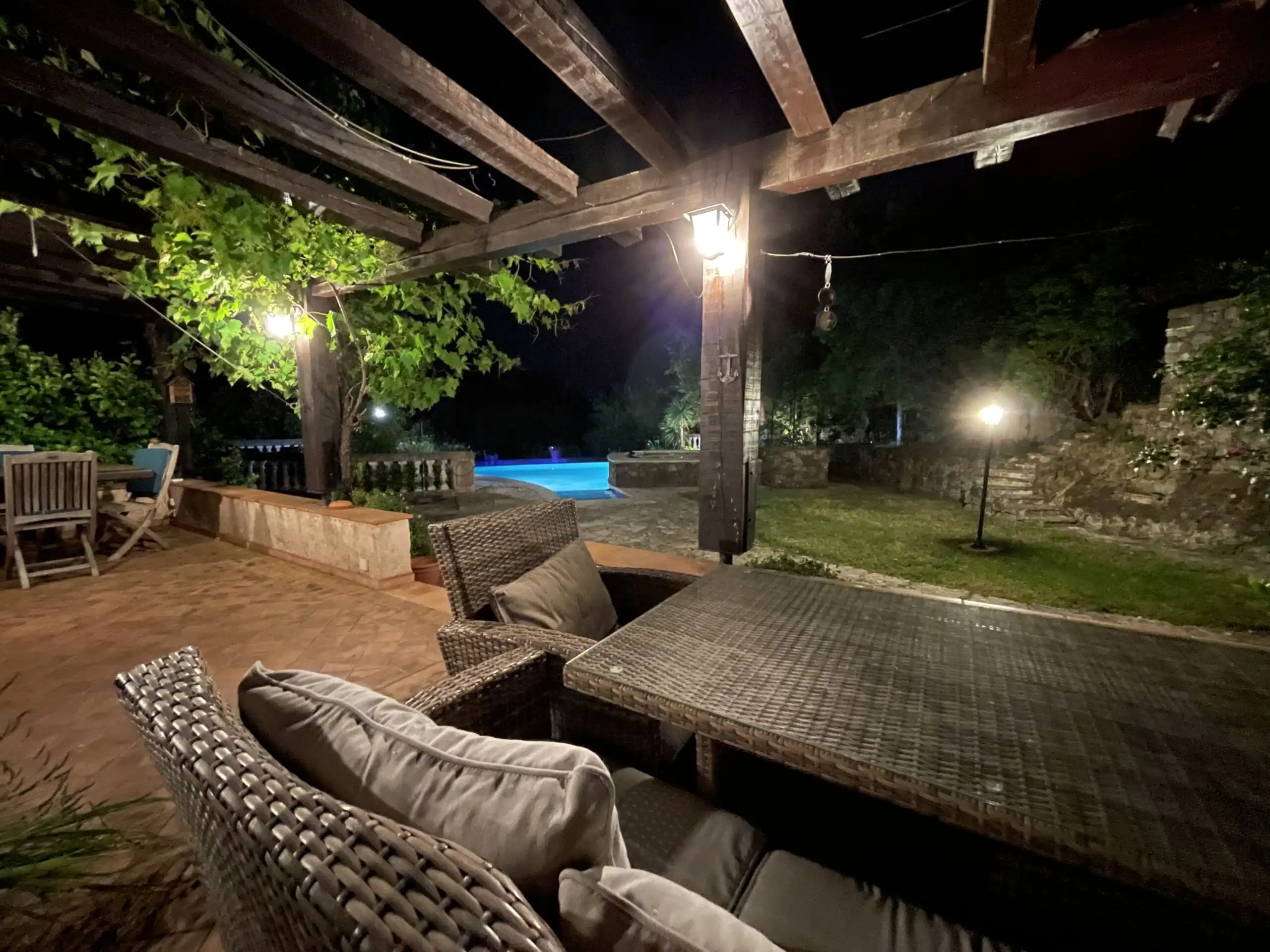 Outdoor lounge area with pool and garden at night.