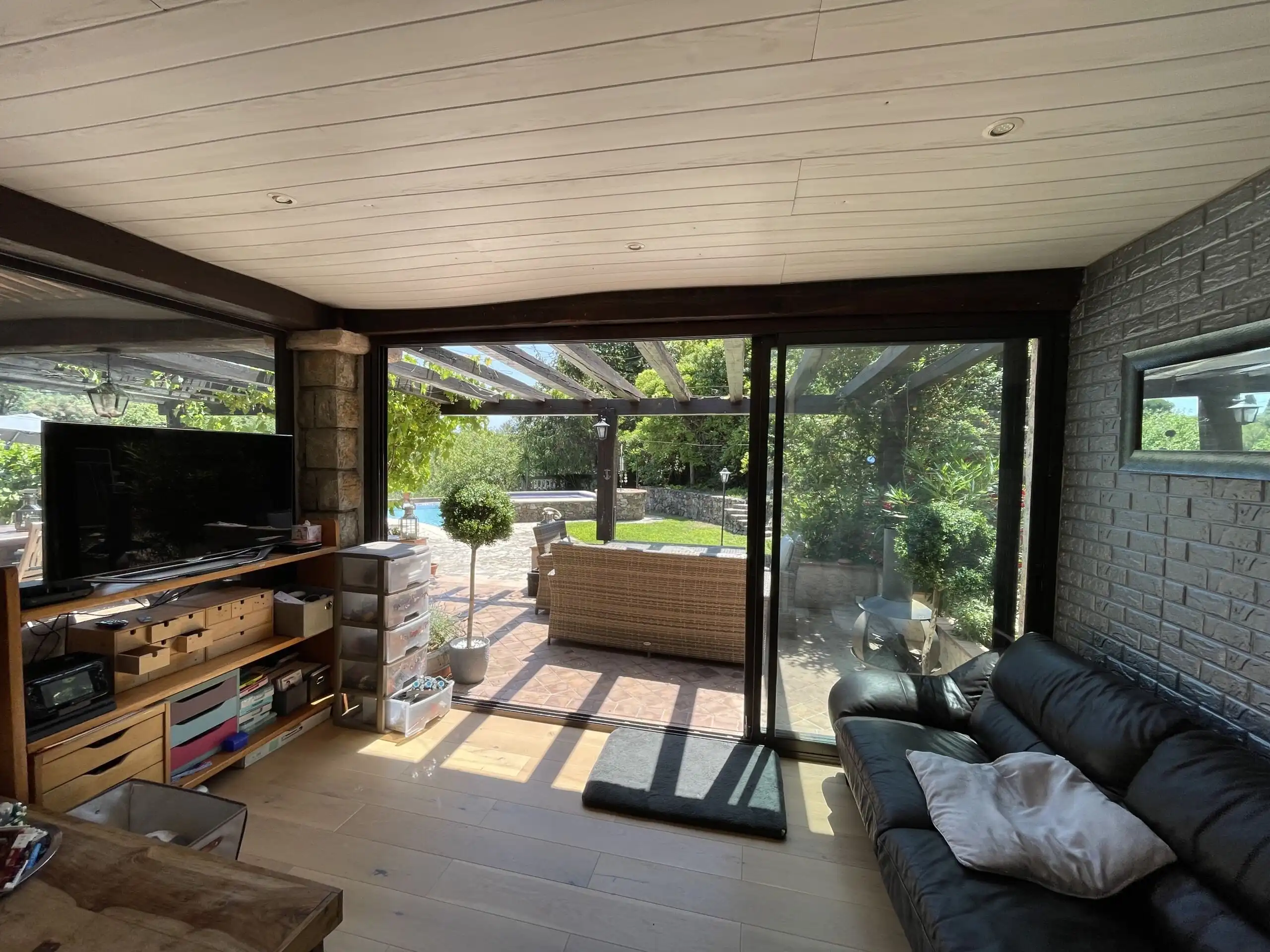 Luxury family villa living room with large glass doors opening to garden and pool area.