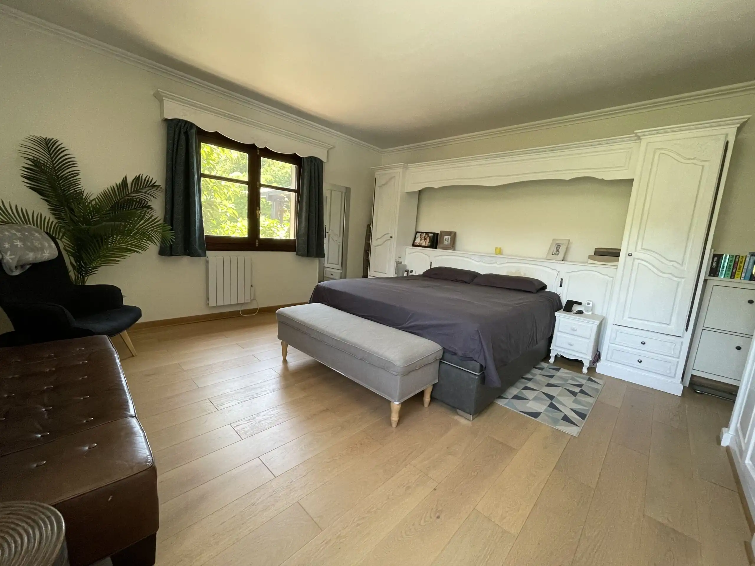 Spacious bedroom with elegant decor, large window, and cozy seating area in a renovated villa.