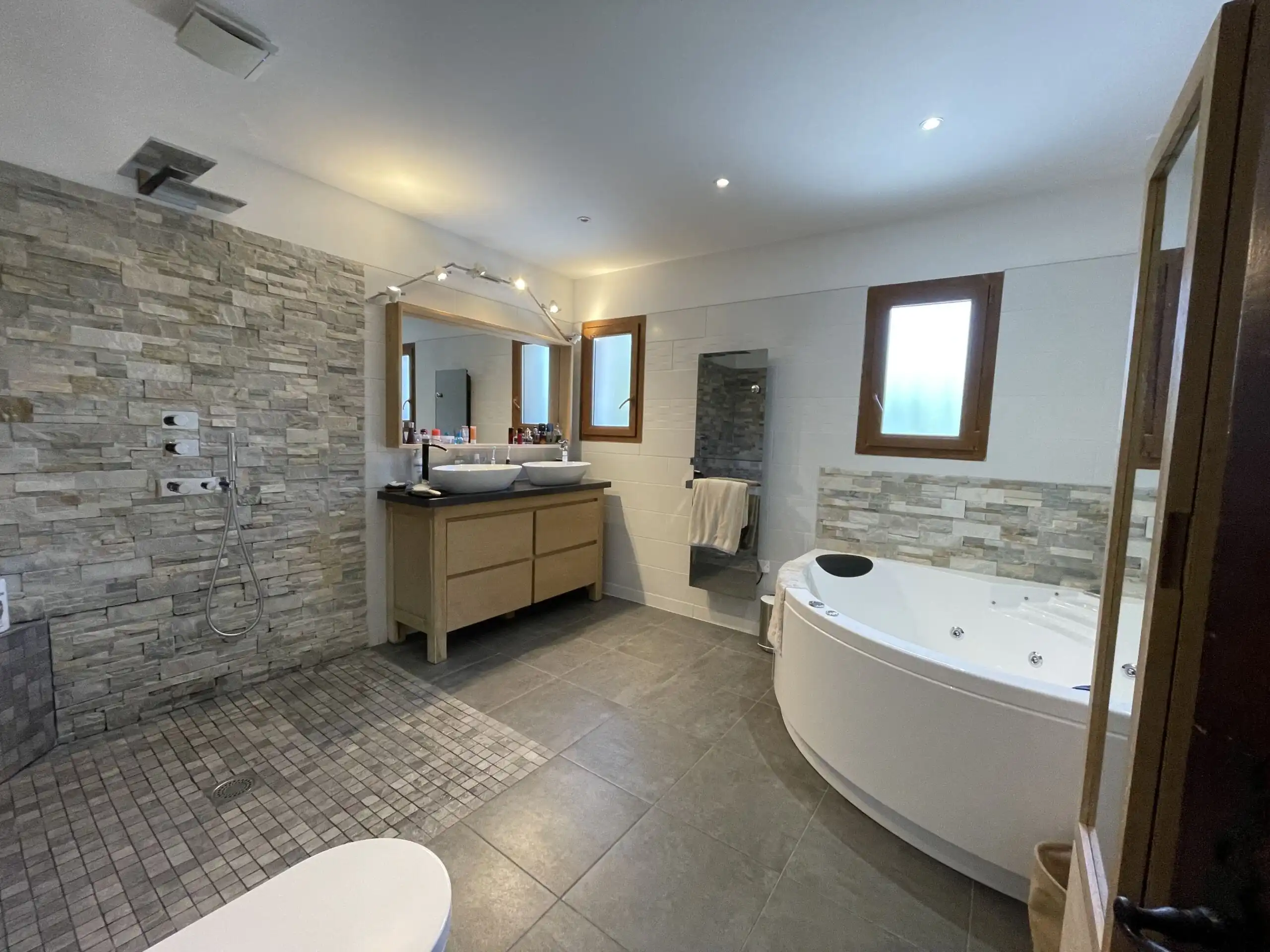 Bathroom with modern fixtures, stone accents, and a large bathtub in Biot, French Riviera.