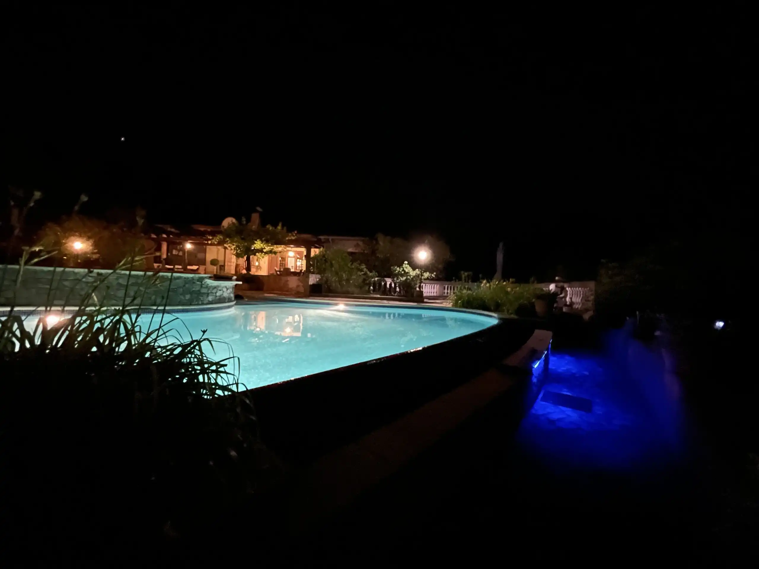 Night view of a luxurious villa with illuminated pool and garden in Biot, French Riviera.