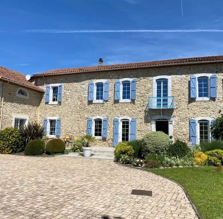 Beautiful stone-built bed and breakfast with blue shutters in Ausson, Haute Garonne, France.