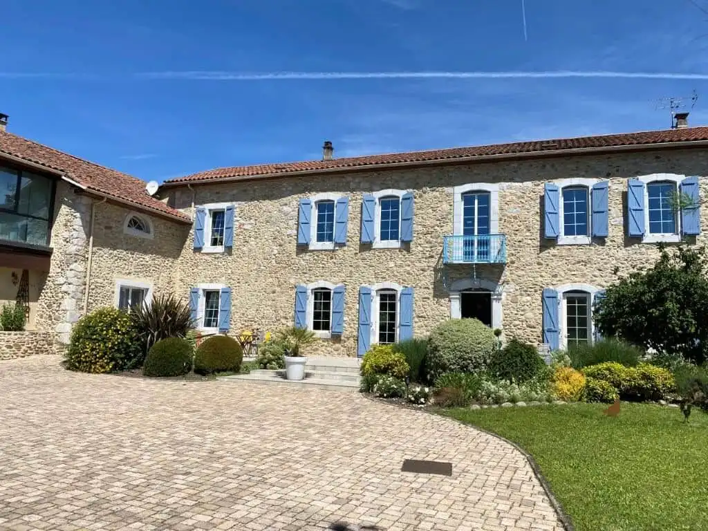 Beautiful stone-built bed and breakfast with blue shutters in Ausson, Haute Garonne, France.