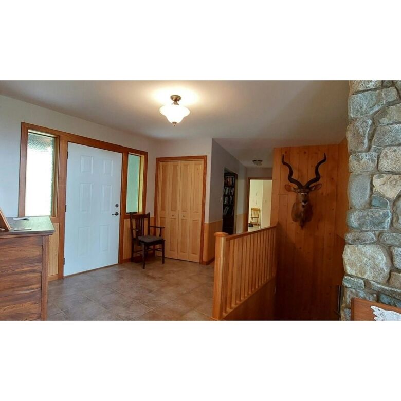 Entrance hall with wooden accents and stone wall feature in Bella Coola estate.
