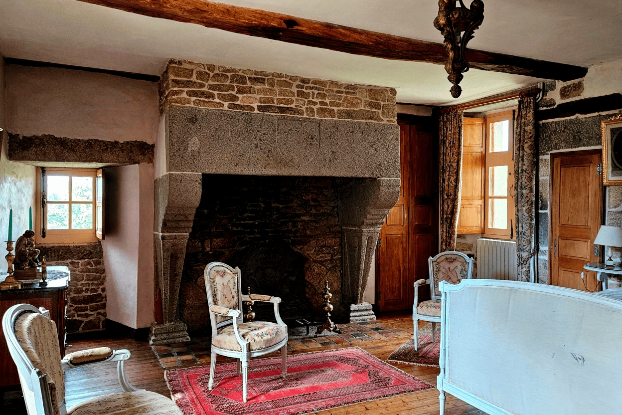 Luxury 5 Bed Le Manoir de Dougeru Charming interior of Le Manoir de Dougeru with rustic stone fireplace and vintage furniture.
