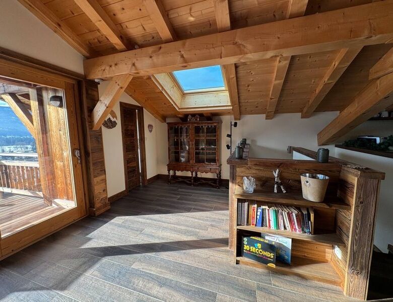 Chalet interior with wooden beams, large windows, and mountain views in Samoens.