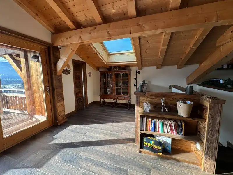 Chalet interior with wooden beams, large windows, and mountain views in Samoens.