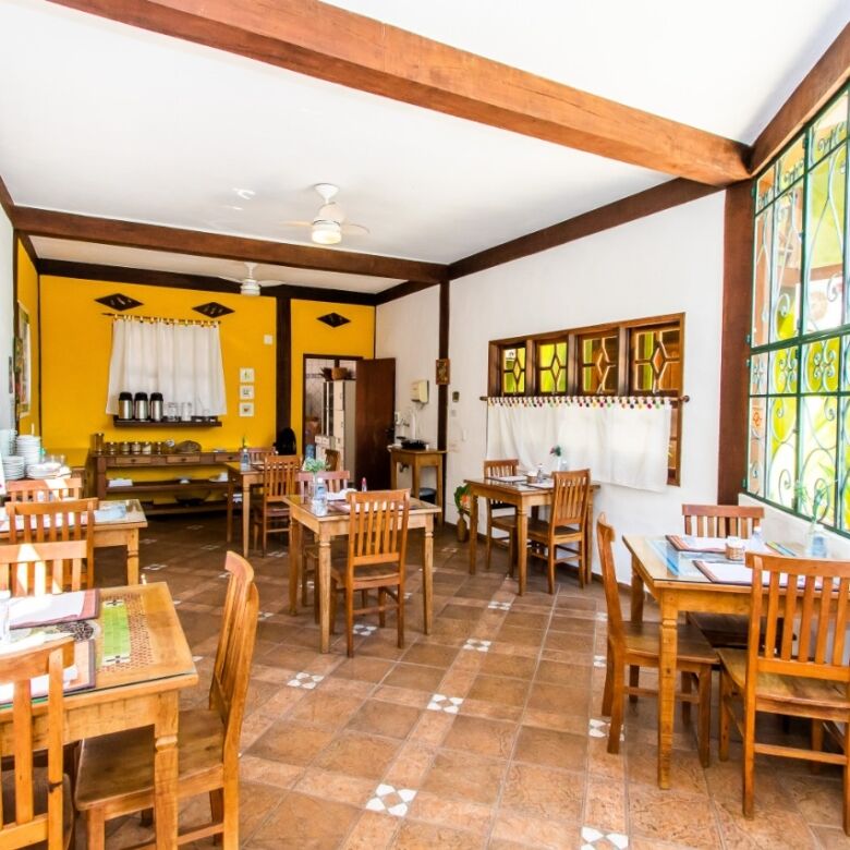 Boutique hotel interior with cozy dining area, wooden furniture, and large decorative windows in Ilh.