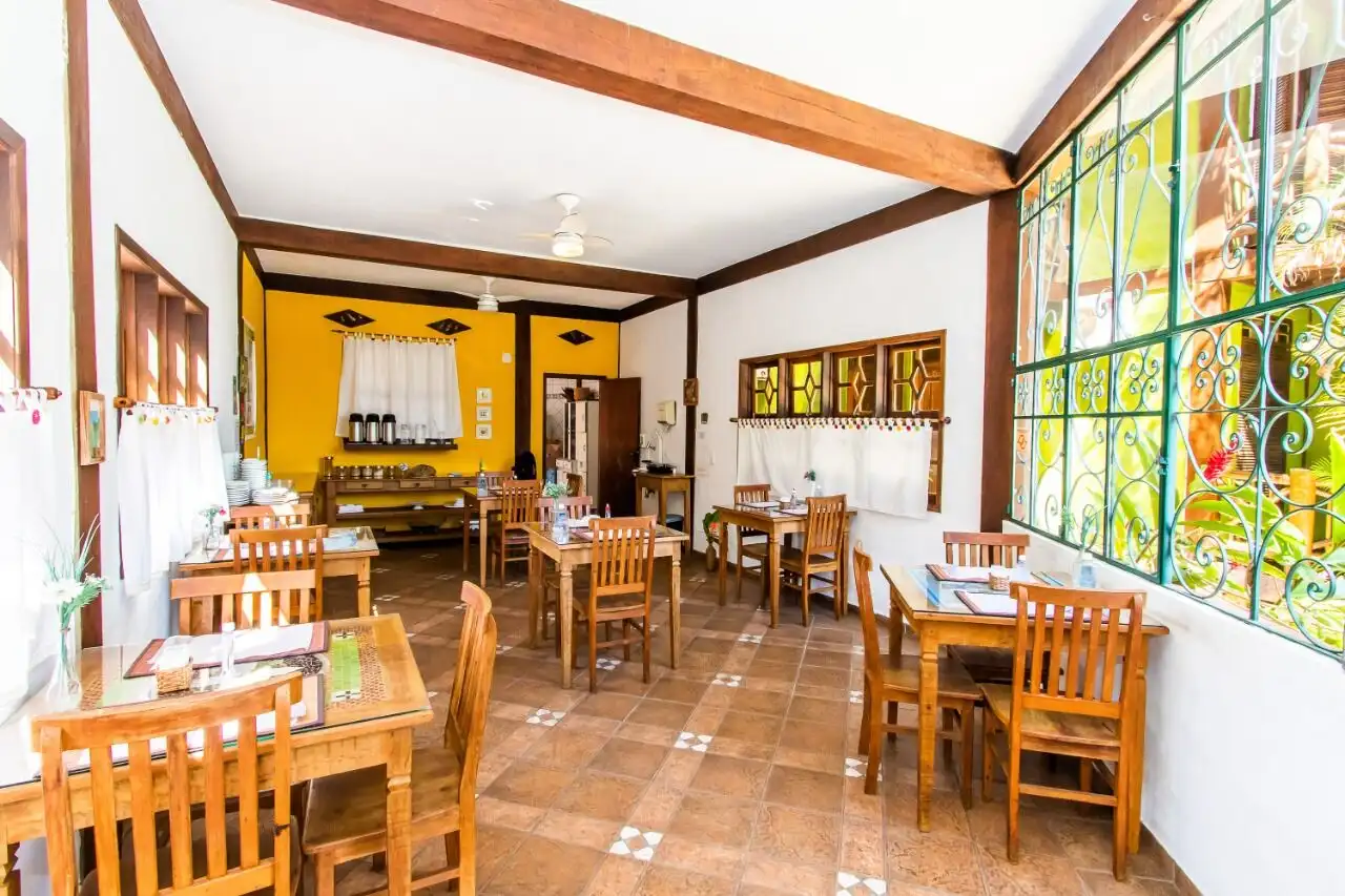 Boutique hotel interior with cozy dining area, wooden furniture, and large decorative windows in Ilh.