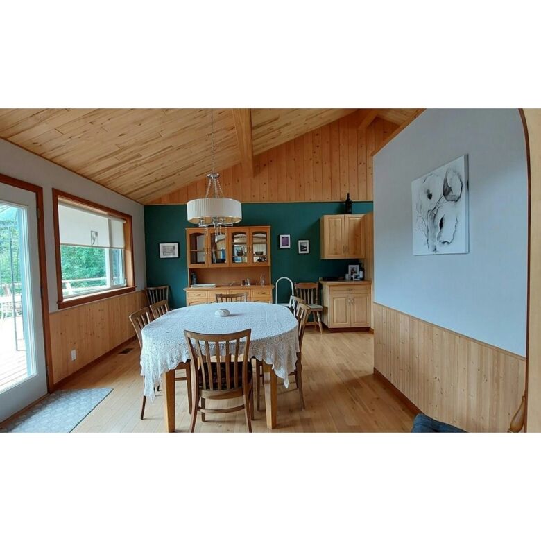 Spacious dining area with natural light and wooden accents in Bella Coola estate. Perfect for family.