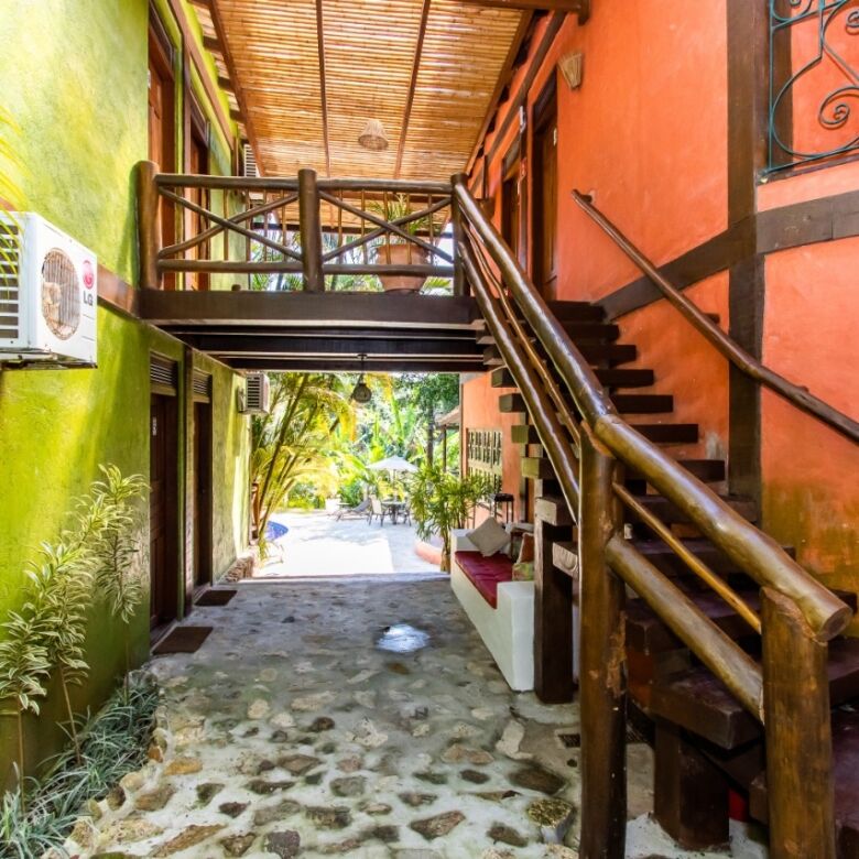 Colorful boutique hotel entrance with wooden stairs and lush greenery in Ilhabela.