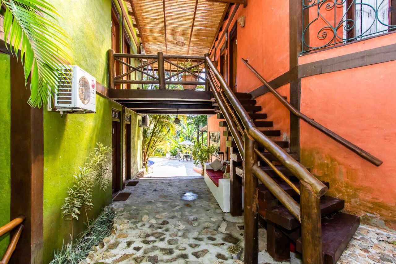 Charming Boutique Hotel Entrance Colorful boutique hotel entrance with wooden stairs and lush greenery in Ilhabela.
