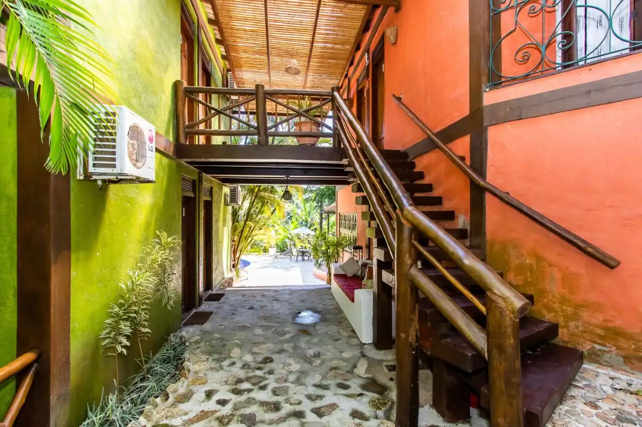 Colorful boutique hotel entrance with wooden stairs and lush greenery in Ilhabela.