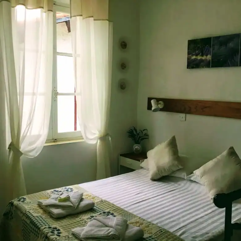Spacious bedroom with natural light, white curtains, and cozy bedding in the La Chataigneraie Gite c.