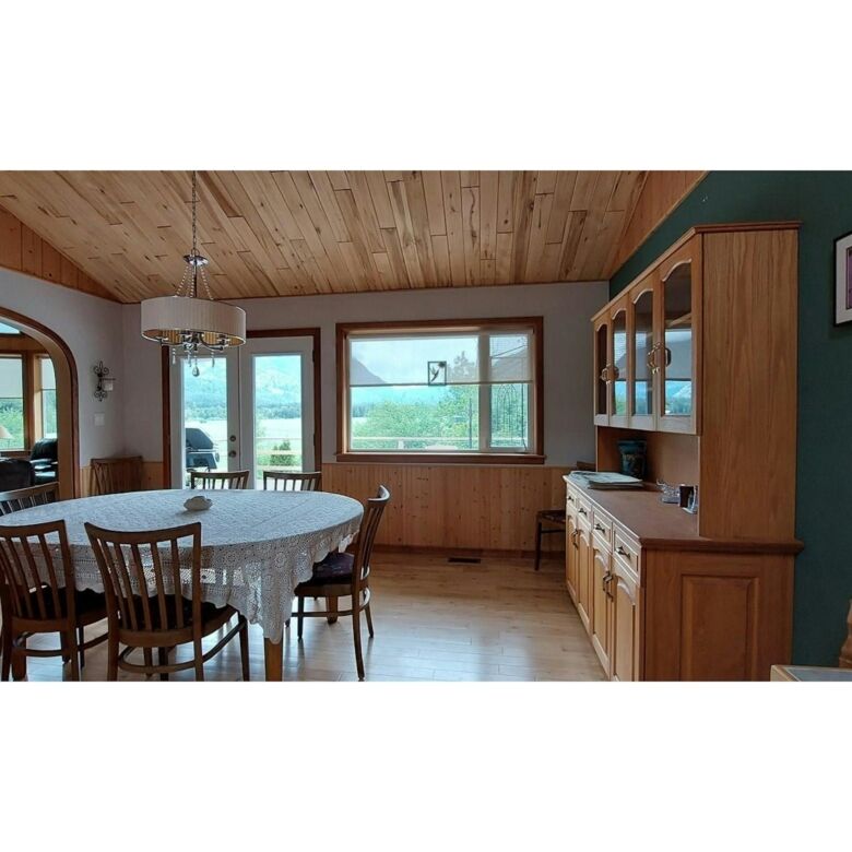 Spacious dining room with wooden ceiling and large windows offering scenic views in Bella Coola esta.