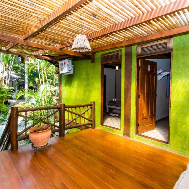 Cozy boutique hotel room with vibrant green walls and wooden accents in Ilhabela. Perfect for a rela.