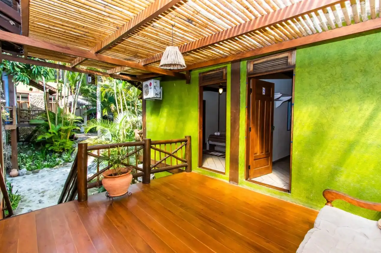 Cozy boutique hotel room with vibrant green walls and wooden accents in Ilhabela. Perfect for a rela.
