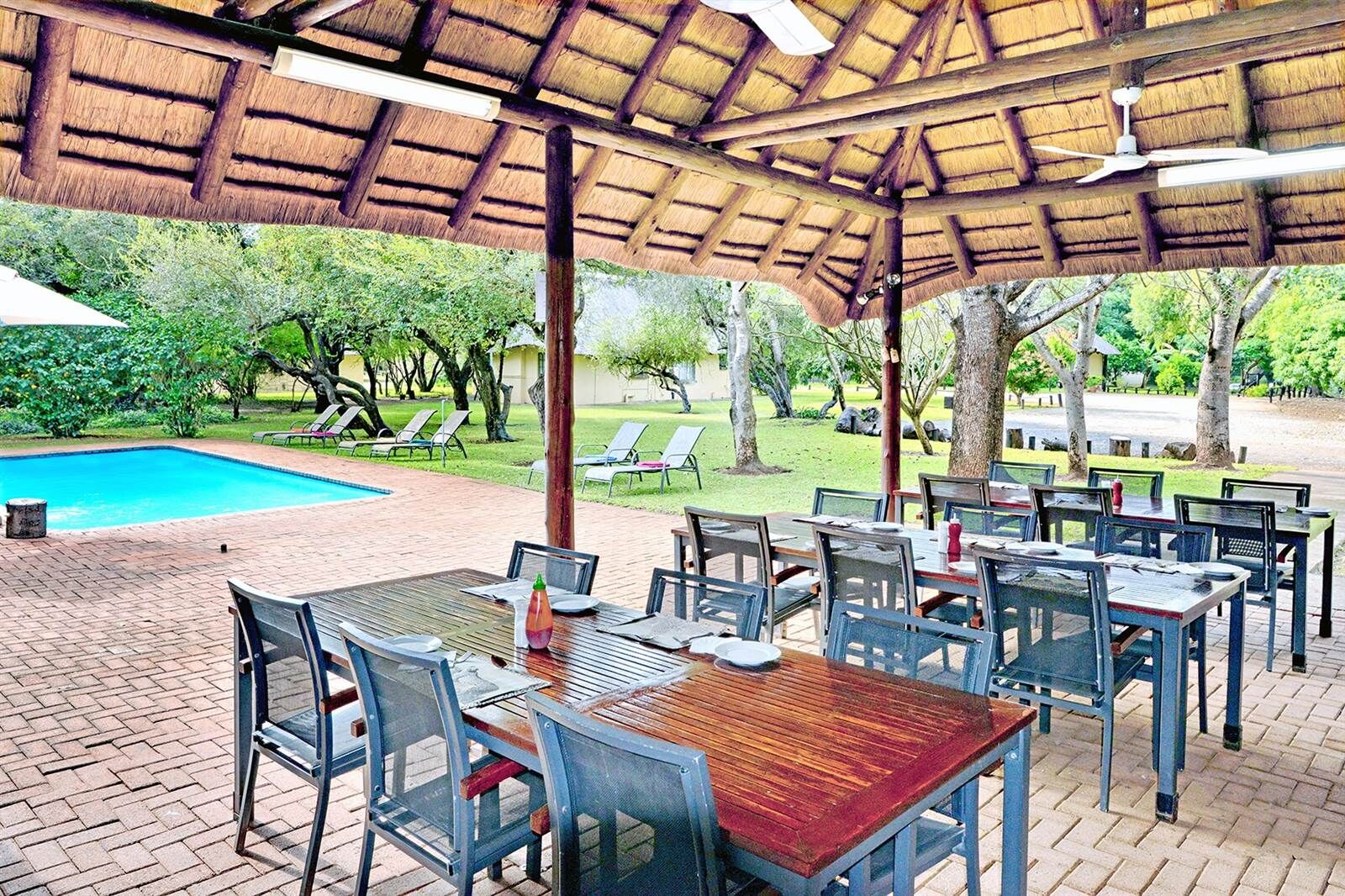 Outdoor dining area at Komati River Chalets with pool and lush garden views.
