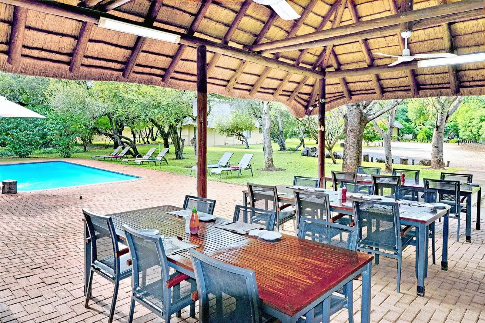 Outdoor dining area at Komati River Chalets with pool and lush garden views.
