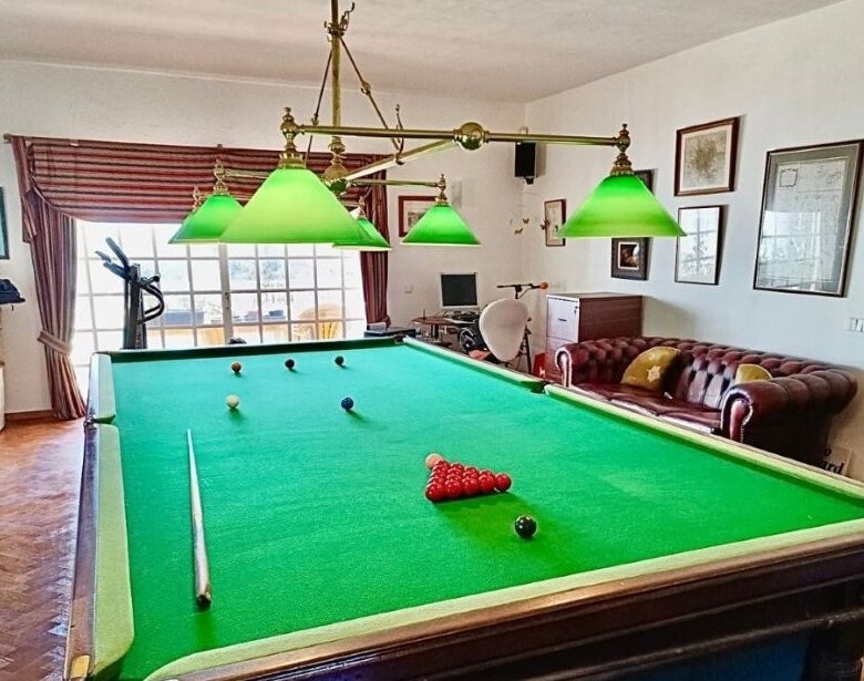 Elegant billiard room with green felt pool table and classic decor.