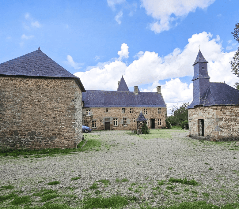 Le Manoir de Dougeru historic stone manor in Normandy, France, with towers and lush surroundings.