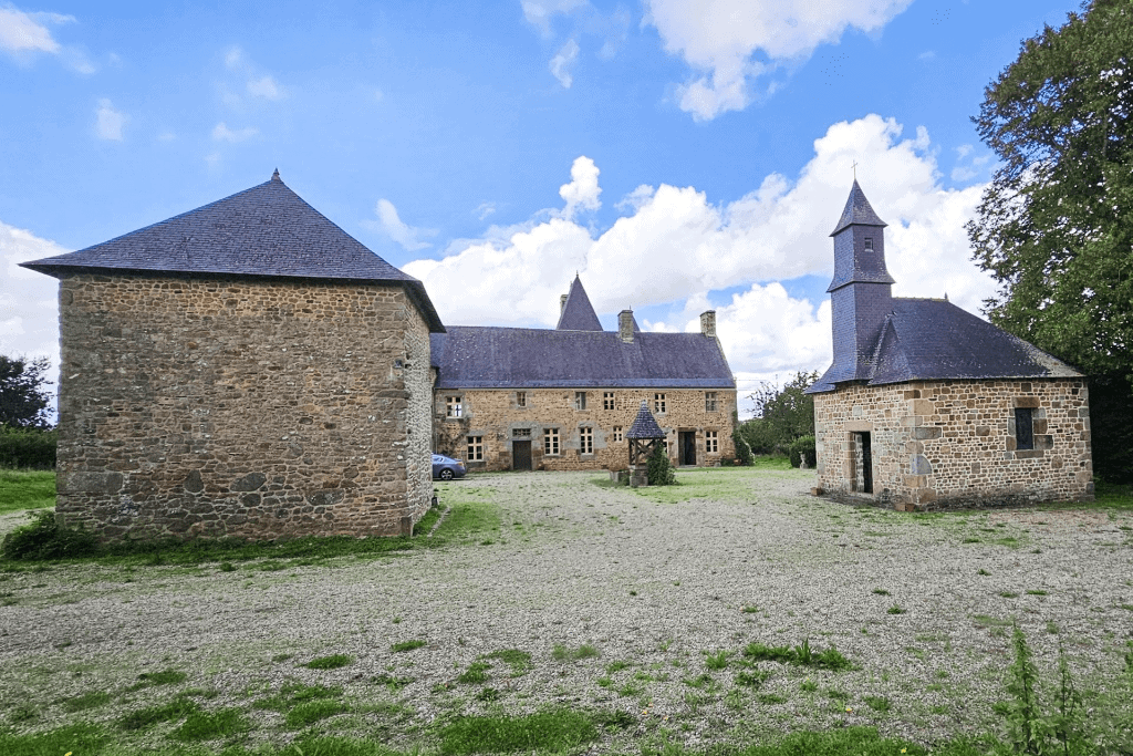 Luxury 5 Bed Le Manoir de Dougeru Le Manoir de Dougeru historic stone manor in Normandy, France, with towers and lush surroundings.