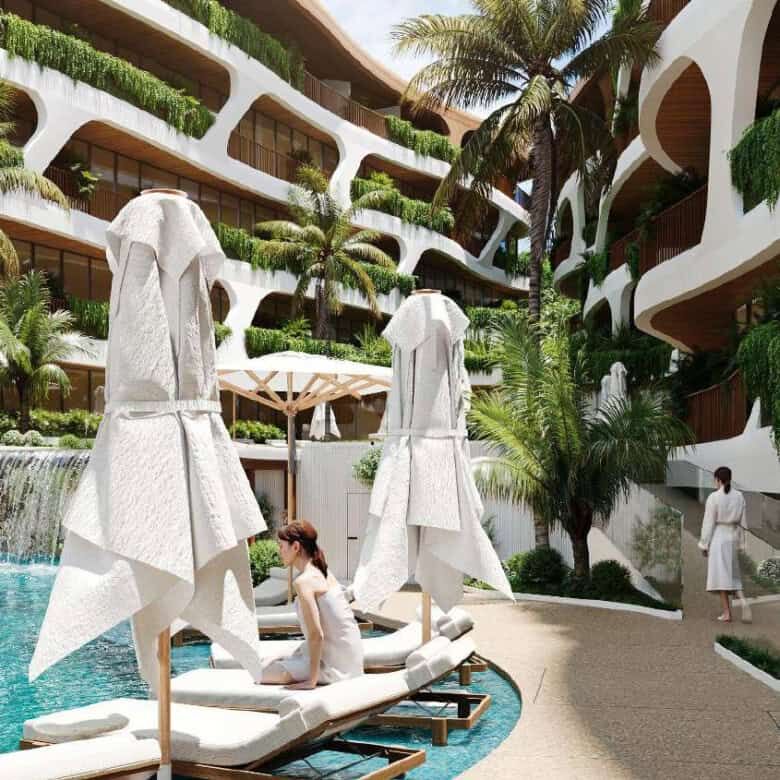 Modern Bali apartment complex with pool and lush greenery.