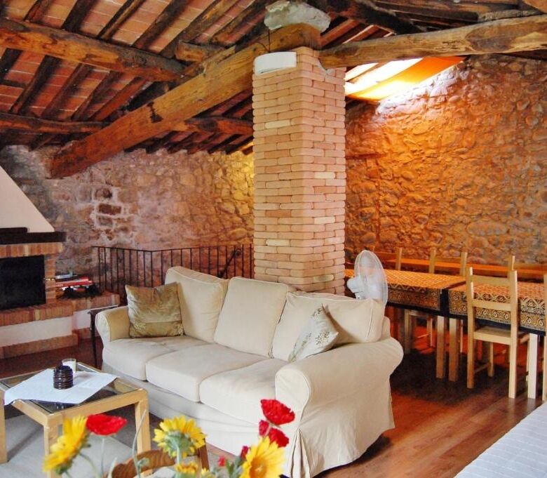 Charming rustic living room with exposed brick walls and wooden beams in a luxury Bagni di Lucca pro.