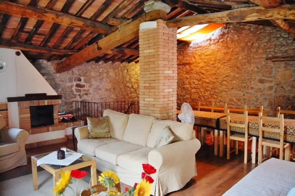 Charming rustic living room with exposed brick walls and wooden beams in a luxury Bagni di Lucca pro.