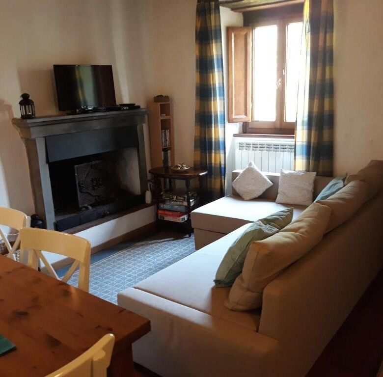 Spacious living room with fireplace, large window, and cozy seating in Bagni di Lucca.