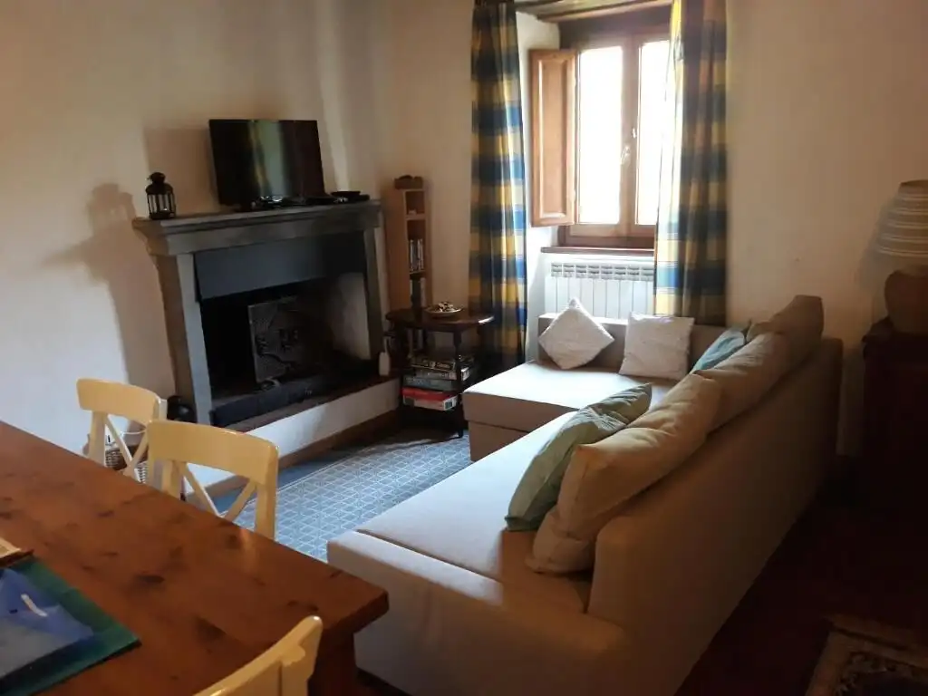 Spacious living room with fireplace, large window, and cozy seating in Bagni di Lucca.
