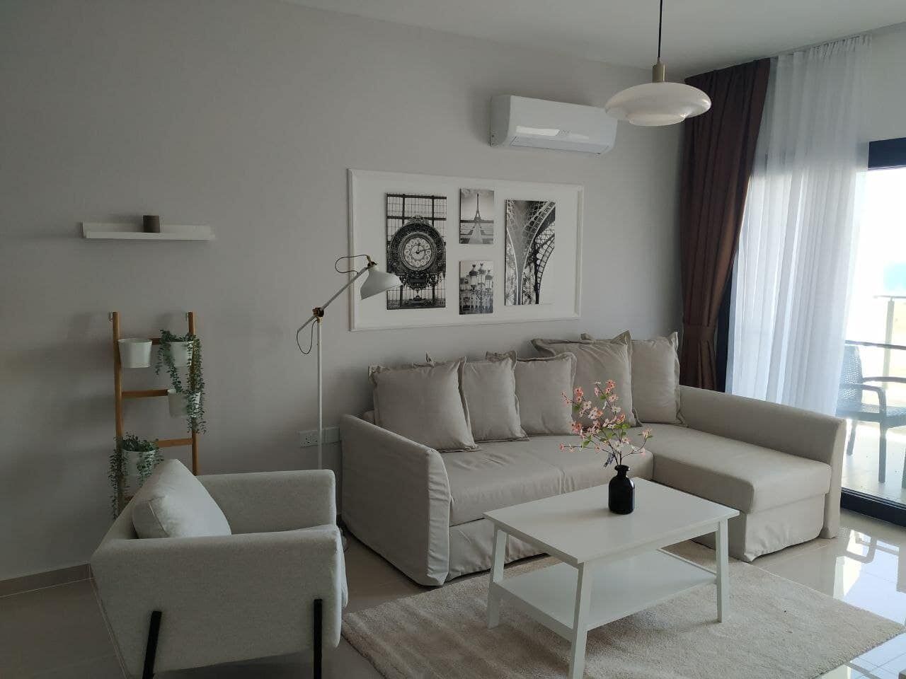 Bright living room with beige sofa, armchair, and balcony view in Caeser’s Resort North.