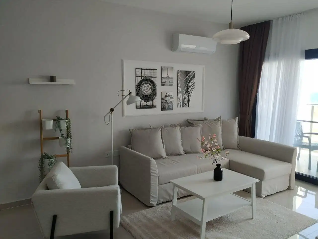 Bright living room with beige sofa, armchair, and balcony view in Caeser’s Resort North.