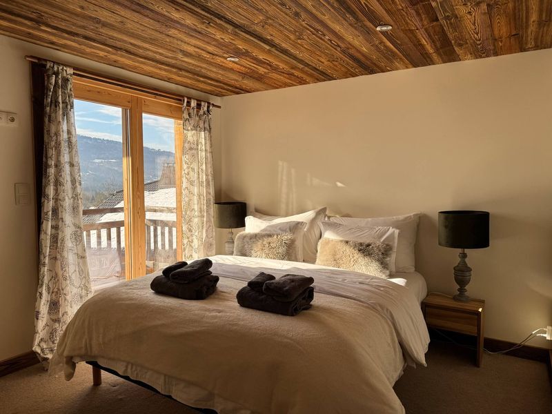 Luxury 5 Bed Chalet Bedroom Cozy bedroom in a luxury chalet with wooden ceiling and large windows overlooking scenic mountain vi.