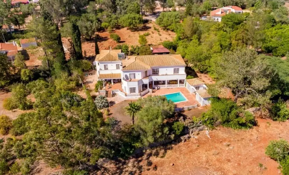 Aerial view of a luxury 5-bedroom country estate with pool in Algoz, Algarve, surrounded by lush gre.