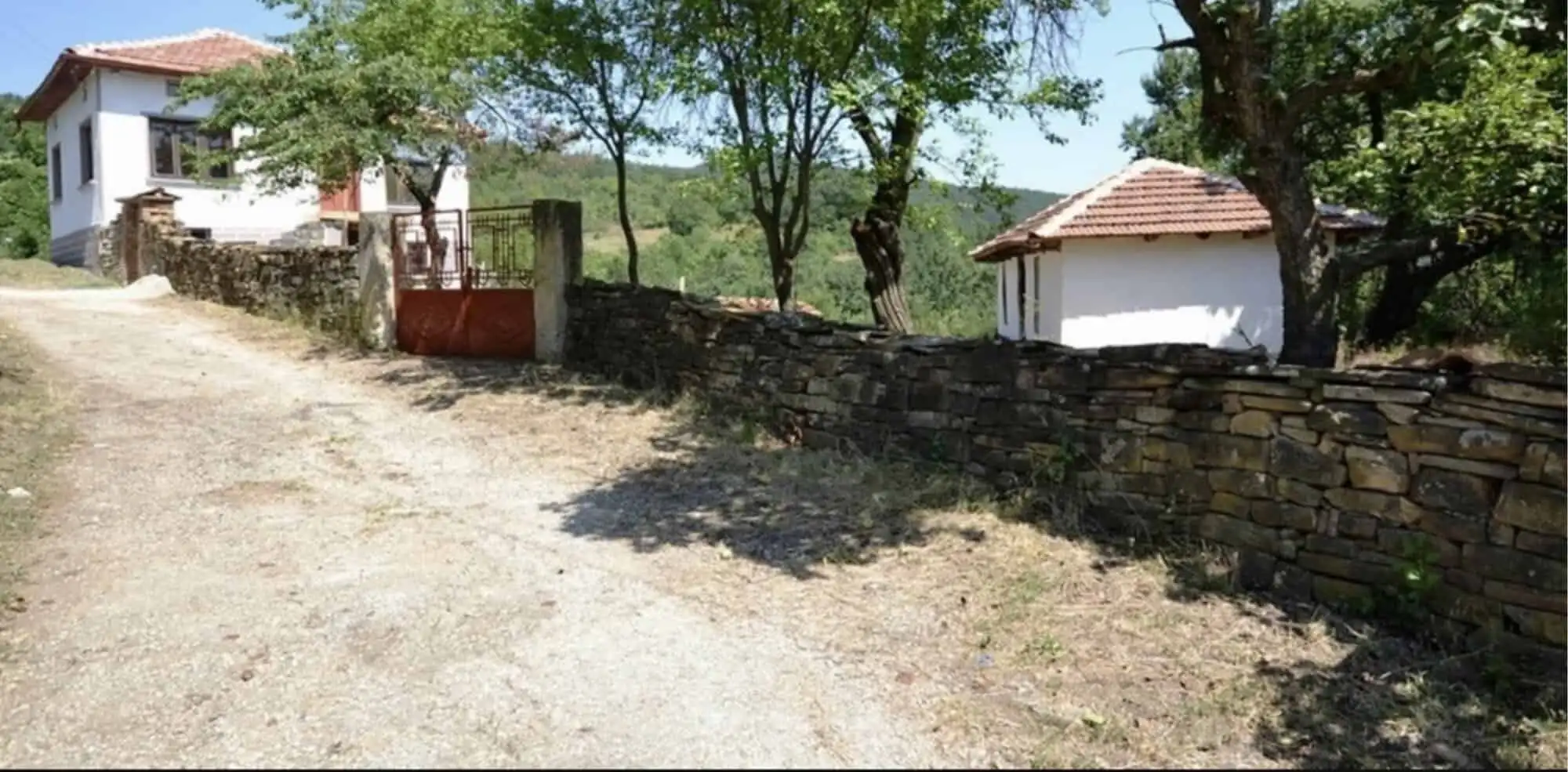 Beautiful view of traditional Bulgarian houses and lush greenery in Rogulyat Mlechevo.