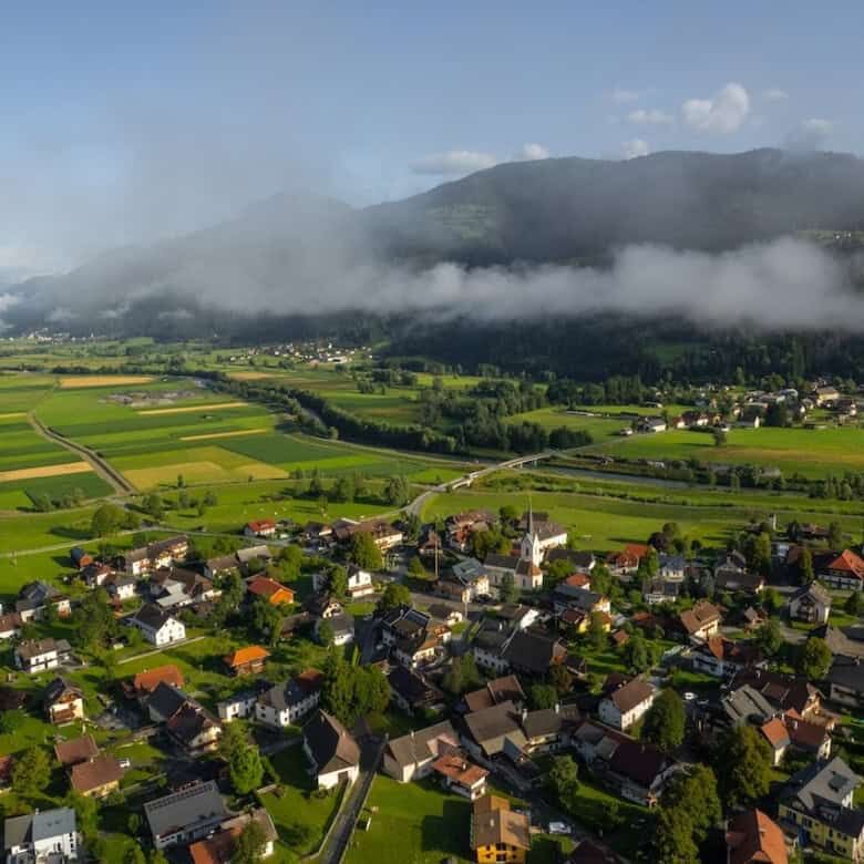 Beautiful aerial view of Rattendorf with lush green fields and mountains in the background.