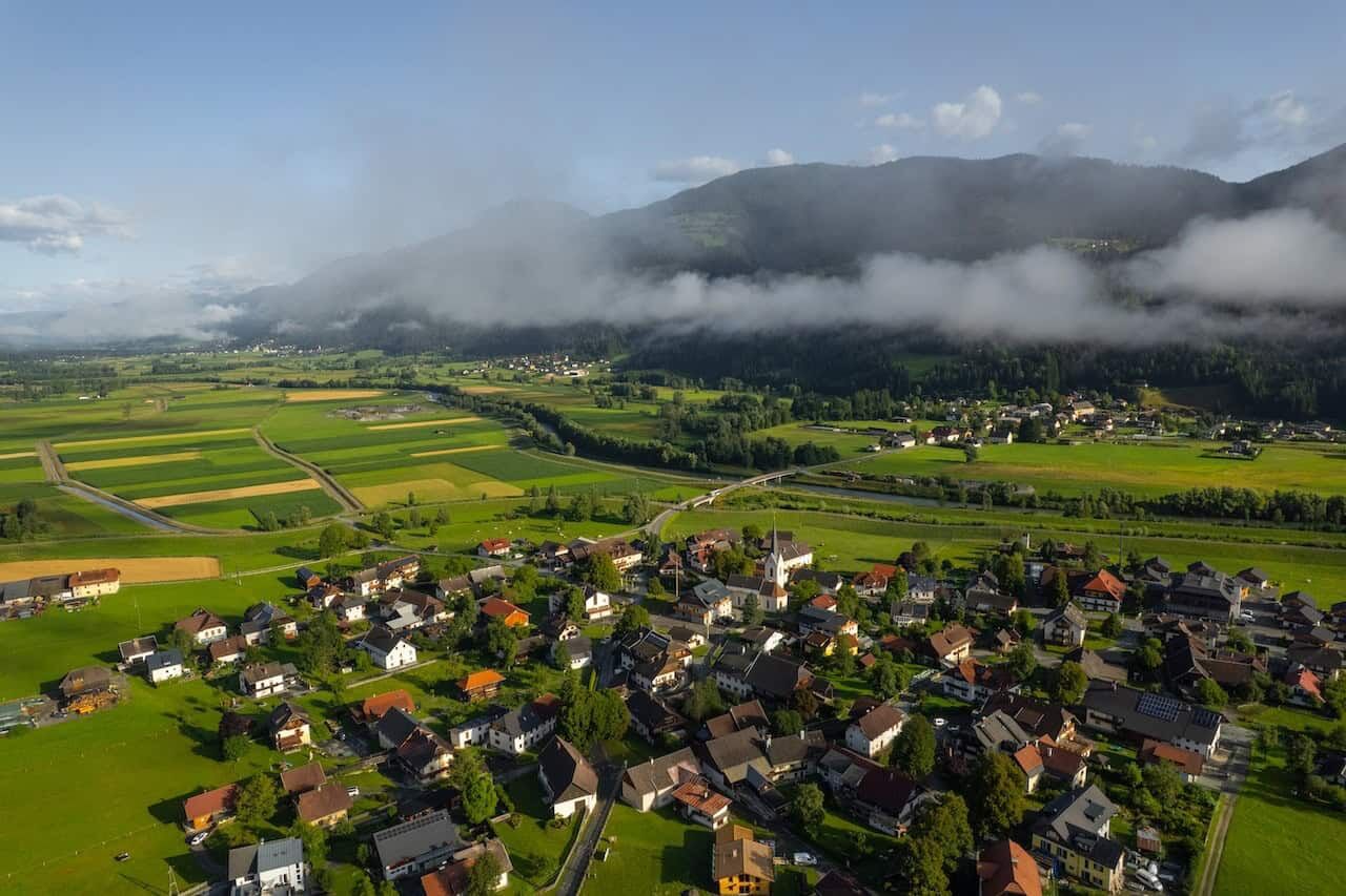 Luxury Apartments in Rattendorf Beautiful aerial view of Rattendorf with lush green fields and mountains in the background.