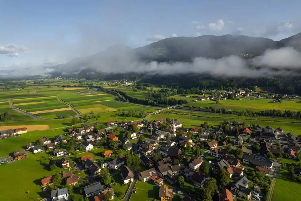 Beautiful aerial view of Rattendorf with lush green fields and mountains in the background.