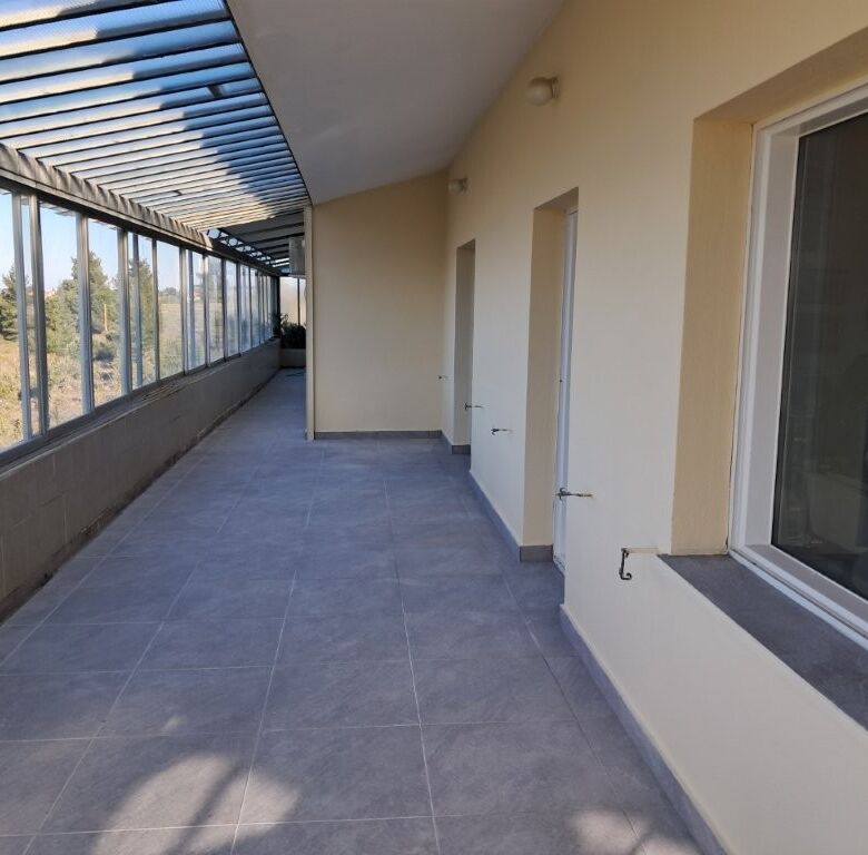 Balcony of a 4-bedroom house in Kapandriti Attica, featuring glass windows and scenic views.