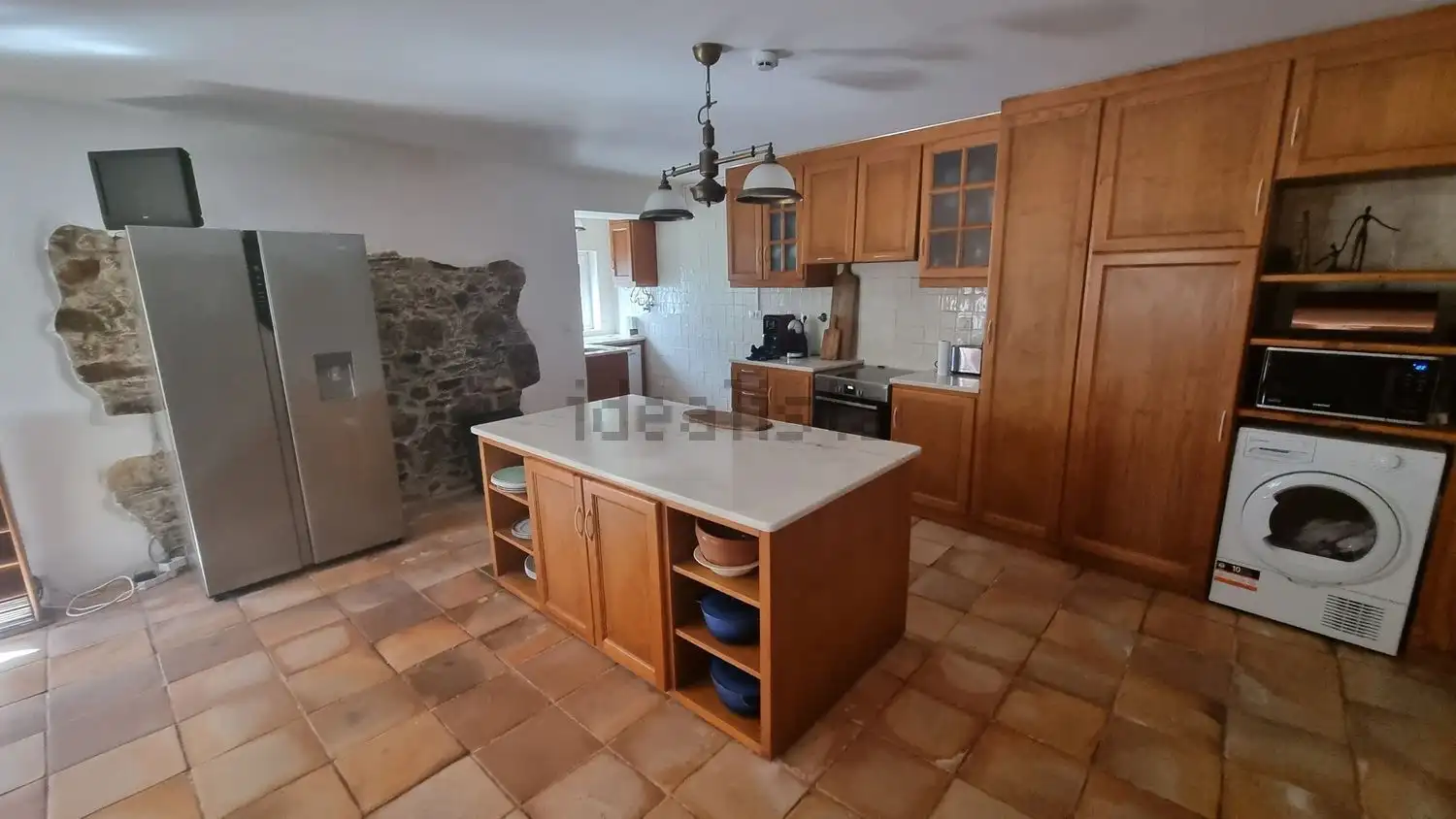 Spacious kitchen featuring wooden cabinetry, a central island, and stone wall details in a beautiful.
