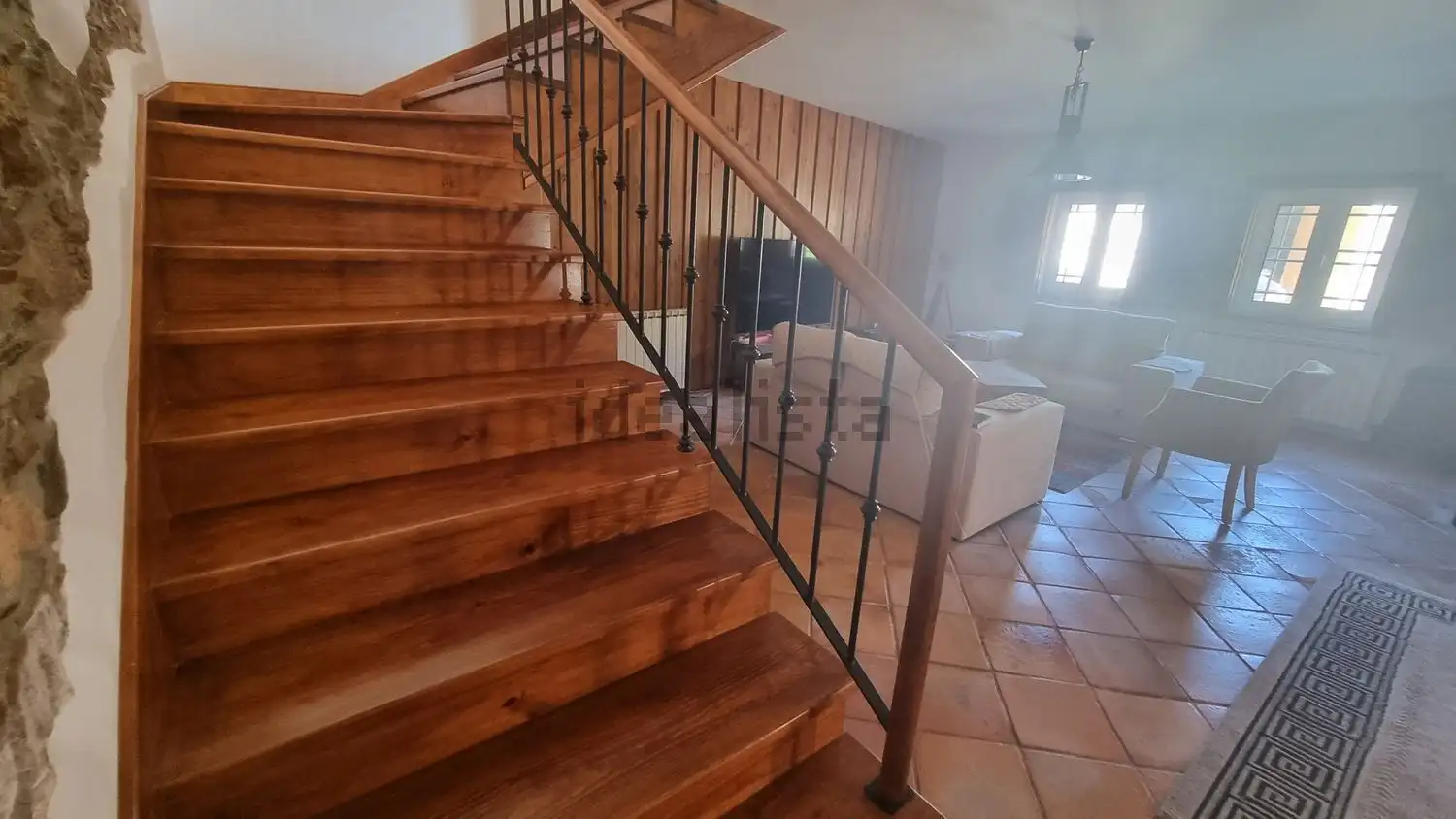 Interior view of a living room featuring wooden stairs and a cozy seating area.