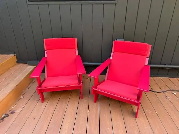 Elegant outdoor seating with red chairs on a wooden deck.