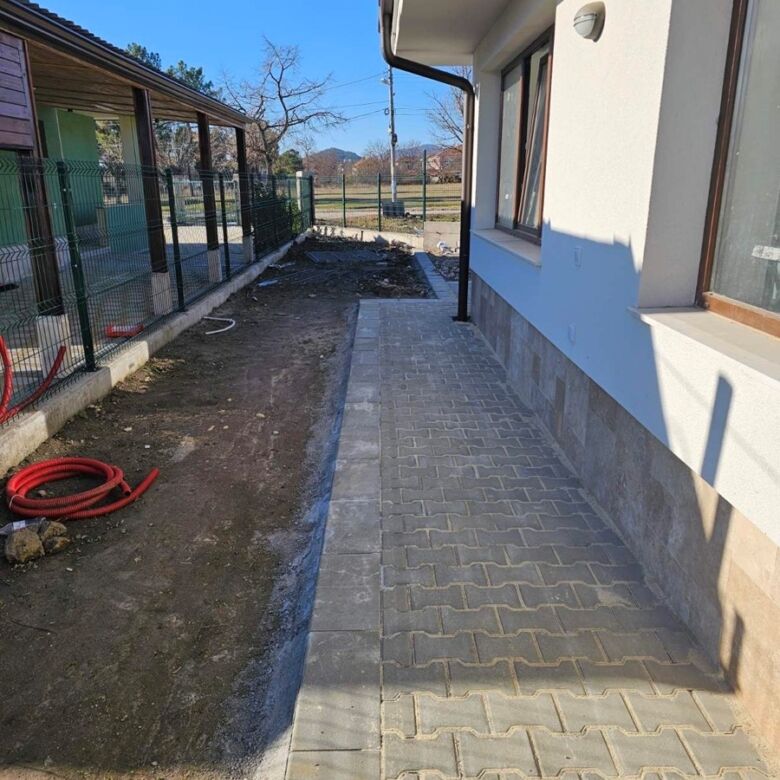 Beautiful exterior view of a 2-bedroom villa in Hissaria, Plovdiv, showcasing a paved walkway and mo.