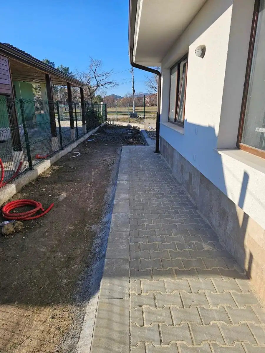 Beautiful exterior view of a 2-bedroom villa in Hissaria, Plovdiv, showcasing a paved walkway and mo.