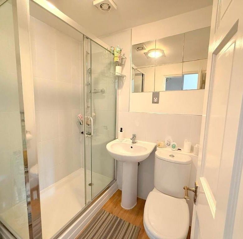 Bathroom with shower, sink, and toilet in a luxury Milton Keynes apartment.